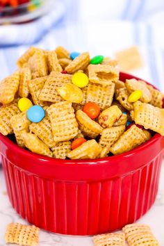 a red bowl filled with cheetos and m & m candies on top of a table