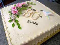 a birthday cake with the number 80 on it, decorated with flowers and greenery