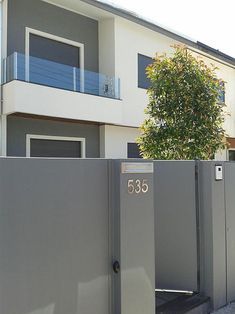 a fenced in area next to a building with a tree on the other side