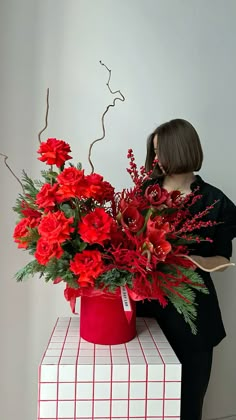 a woman sitting on top of a red box holding a bouquet of flowers in her hands