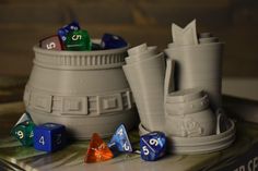 several different colored dice sitting on top of a table next to a cup and book