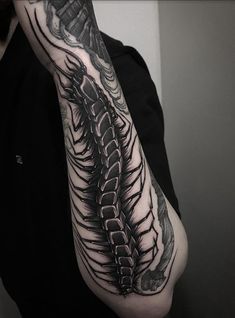 a man's arm with a black and white tattoo design on the left arm