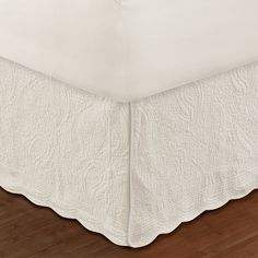 a white bedspread on a wooden floor