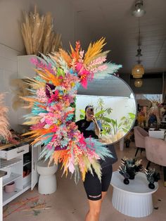 a woman taking a selfie in front of a mirror with colorful feathers on it