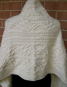 a white knitted shawl hanging on a brick wall