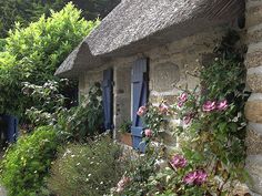 an old stone cottage with blue shutters and flowers