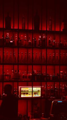 a room filled with lots of bottles and shelves covered in red lights at night time