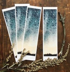 three cards with trees on them sitting next to dried flowers