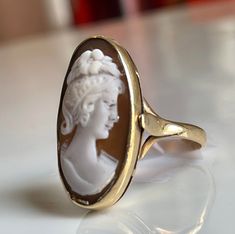 Cameo ring; 14k solid gold. The hand carving in this piece is unusually nice quality and is well preserved. Even the wavy tendrils of her hair and orange blossom crown are still visible. Shell cameo is bezel set and measures 25 mm x 14 mm. The ring shape elongates the finger and looks beautiful on the hand! Details: Ring face measures 25 mm x 14 mm. This is a wonderfully substantial piece! Size 6.5 and can be sized by adding our custom sizing listing to your cart using this link: https://www.ets Victorian Yellow Gold Carved Rings, Victorian Carved Yellow Gold Rings, Formal Carved Yellow Gold Rings, Formal Yellow Gold Carved Rings, Fine Jewelry Carved Yellow Gold Rings, Victorian Oval Carved Rings, Collectible Fine Jewelry Intaglio Rings, Formal Carved Rings In 14k Gold, Formal Carved 14k Gold Ring