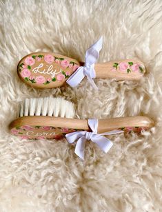 two wooden brushes with floral designs on them sitting on a fluffy white surface next to each other