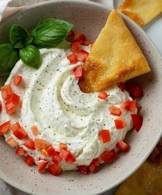 a bowl filled with hummus, tomatoes and tortilla chips