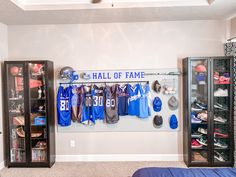 a sports locker with blue and white shirts hanging on it's wall next to a bed