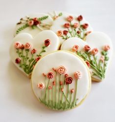 decorated cookies with flowers and leaves are arranged on a white table top, ready to be eaten