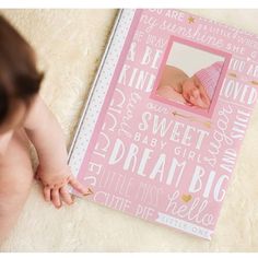 a baby is laying on the floor next to a pink book with words all over it