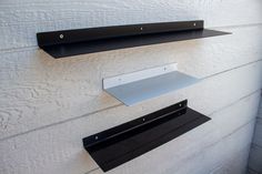 three black and white shelves on the side of a building with metal brackets attached to them