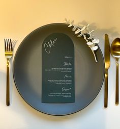 a plate with a menu on it next to silverware and gold cutlery,