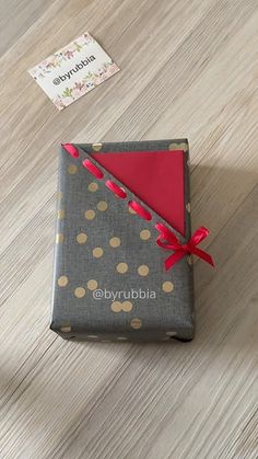 a gift wrapped in grey and gold polka dot paper with a red bow on top