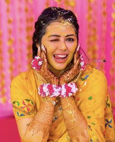 a woman with her hands covered in hendi and flowers on her face, smiling at the camera