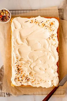 a cake with white frosting and sprinkles sitting on top of parchment paper