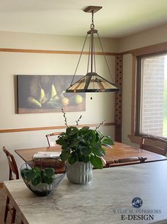 a dining room table with two vases filled with flowers and plants on top of it