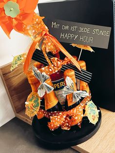 an orange and white bow is on top of a black plate with liquor bottles in it