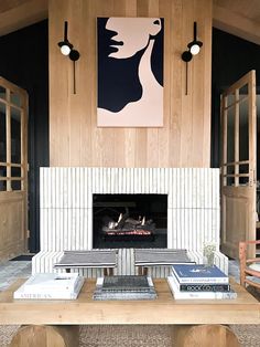 a living room with a fire place and books on the coffee table in front of it