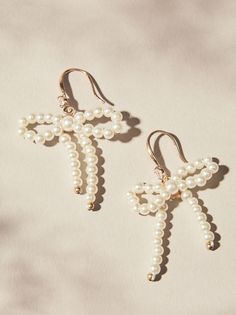 Add a touch of whimsy to your look with our charming pearl bow dangle earrings! Delicate freshwater pearls dangle playfully from shimmering ribbon bows. Pearl Earring Ideas, Pearl Wire Jewelry, Icicle Jewelry, Homemade Earrings Ideas, Hoco Accessories, Diy Pearl Earrings, Gold And Pearl Earrings, Beaded Fish, Bachelorette Accessories