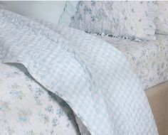 a bed with blue and white flowers on the comforter, pillows and pillow cases