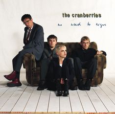 the cranberries sitting on a couch in front of a white wall with words