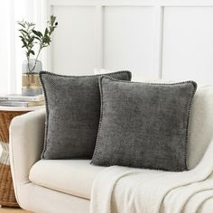 two pillows sitting on top of a white couch