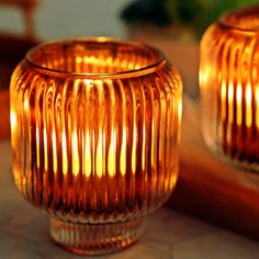 two glass candles sitting on top of a table