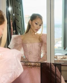 a woman in a pink dress looking into a mirror