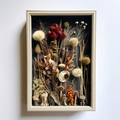 an arrangement of dried flowers in a frame