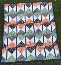 a quilt is laying on the grass with it's blue and orange borders