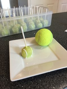 two tennis balls on a plate with toothpicks sticking out of the top one