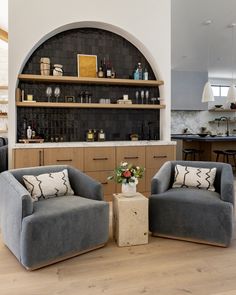 two gray chairs sitting next to each other on top of a hard wood floor