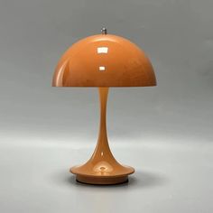 an orange table lamp sitting on top of a white floor