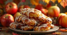 a pile of cinnamon rolls sitting on top of a plate with apples in the background