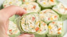 a person is holding a vegetable roll in front of some other food on a plate