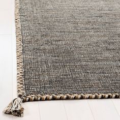 an area rug with tassels on the bottom and fringe at the end in neutral colors