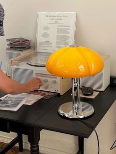 a person sitting at a desk with a yellow lamp on it