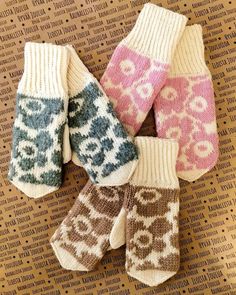 four knitted mittens sitting on top of a cardboard box