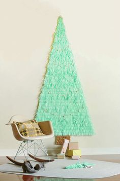 a small green christmas tree sitting on top of a table next to a rocking chair