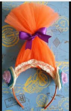 an orange headband with purple and white bows on it's side, sitting on top of a blue table