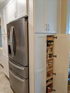 a stainless steel refrigerator freezer sitting inside of a kitchen next to white cupboards