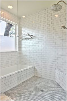 a white tiled bathroom with a large window and shower head in the corner is shown