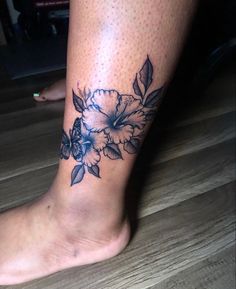 a woman's foot with a flower tattoo on the side of her leg,