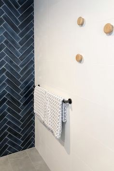 a white towel hanging on the side of a wall next to a blue tiled shower