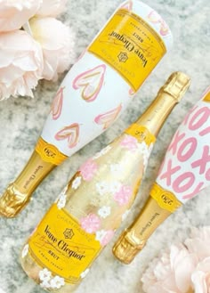 two champagne bottles sitting next to each other on a table with flowers and paper decorations