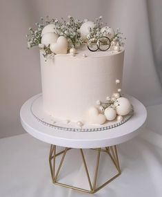 a white wedding cake with flowers and rings on top